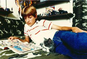 Image of Ryan White reading a comic book with his cat on his bedroom floor.
